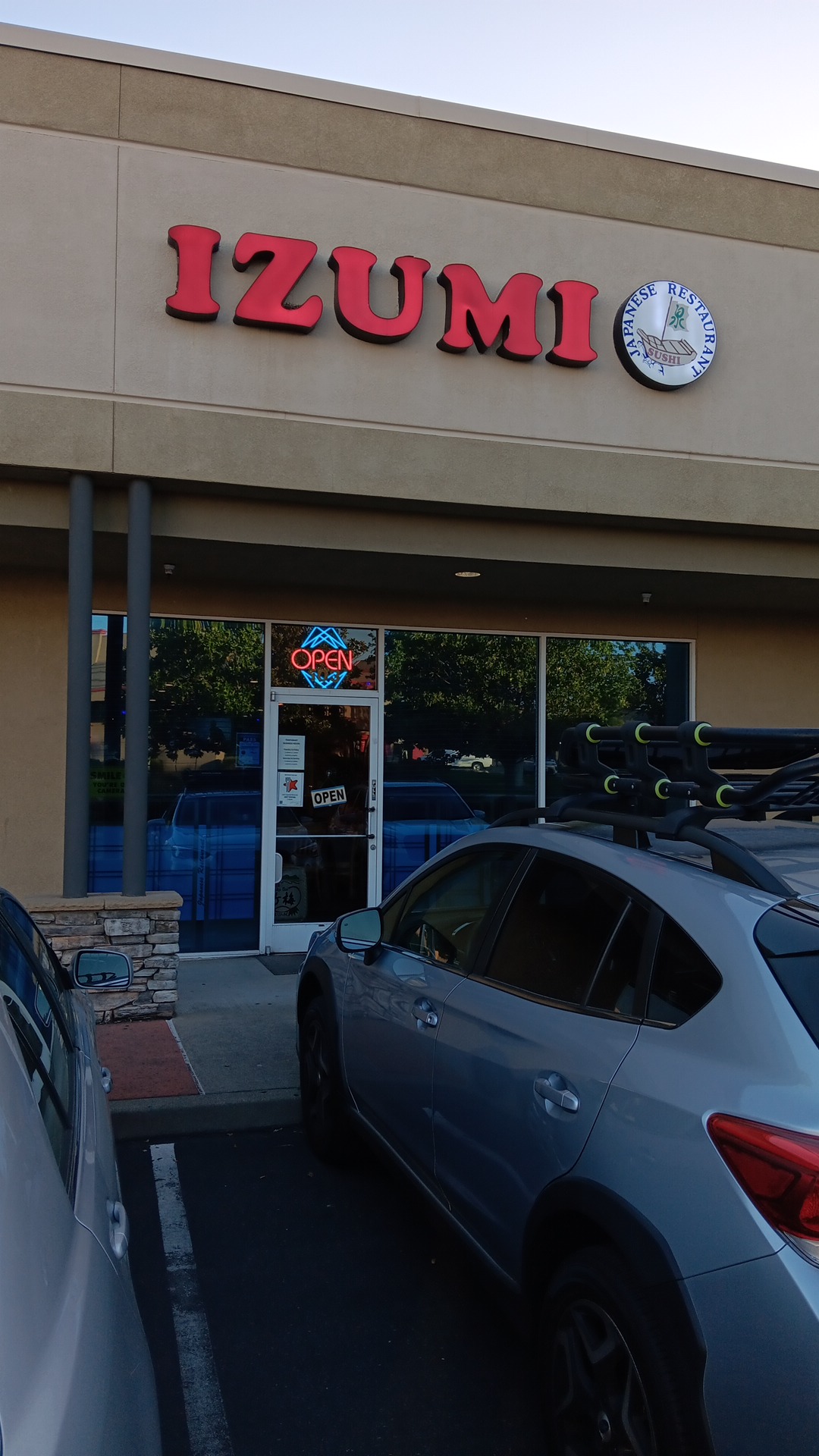 Izumi storefront with red lettering and a round clock on a gray facade